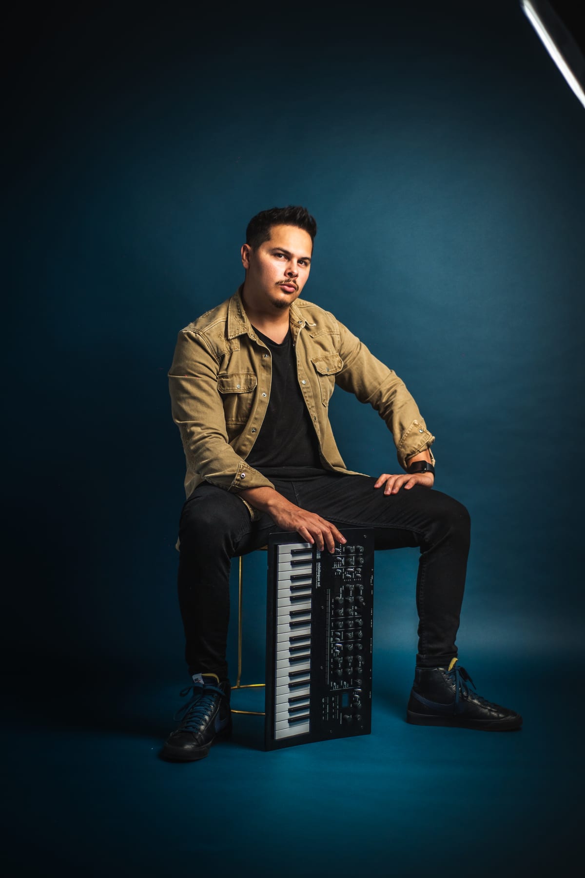 Hanstler seated beside an analog synthesizer in a blue-lit studio