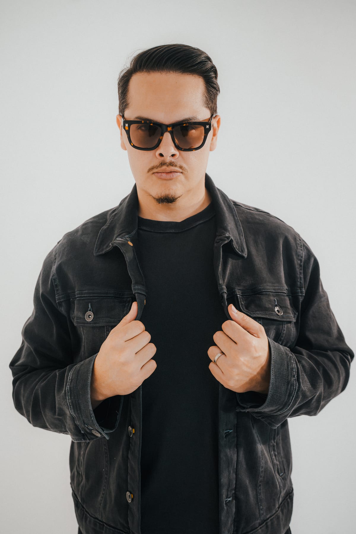 Hanstler wearing sunglasses and a denim jacket — studio portrait